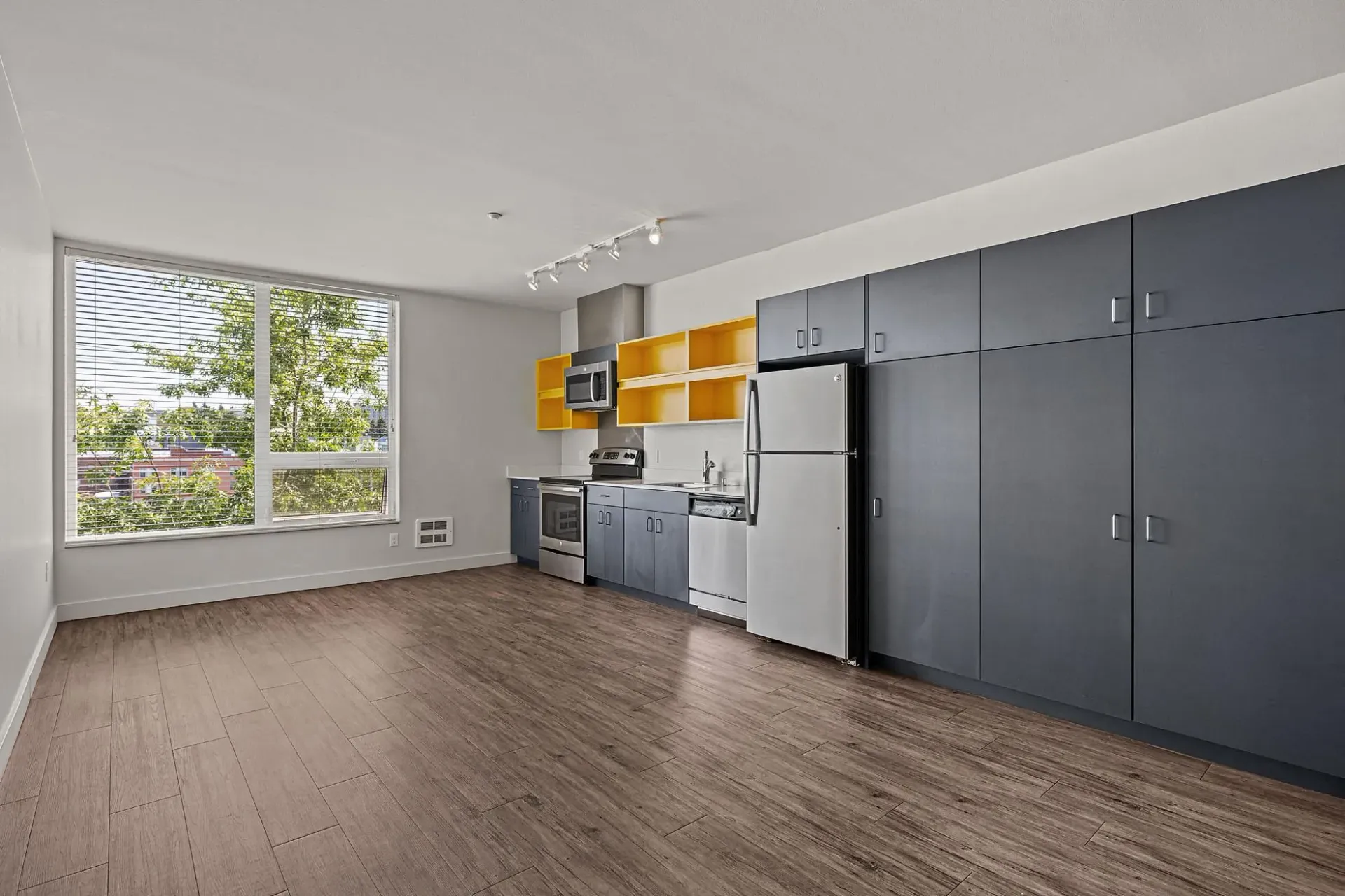 Modern kitchen with dark cabinets, stainless steel appliances, and yellow accents.