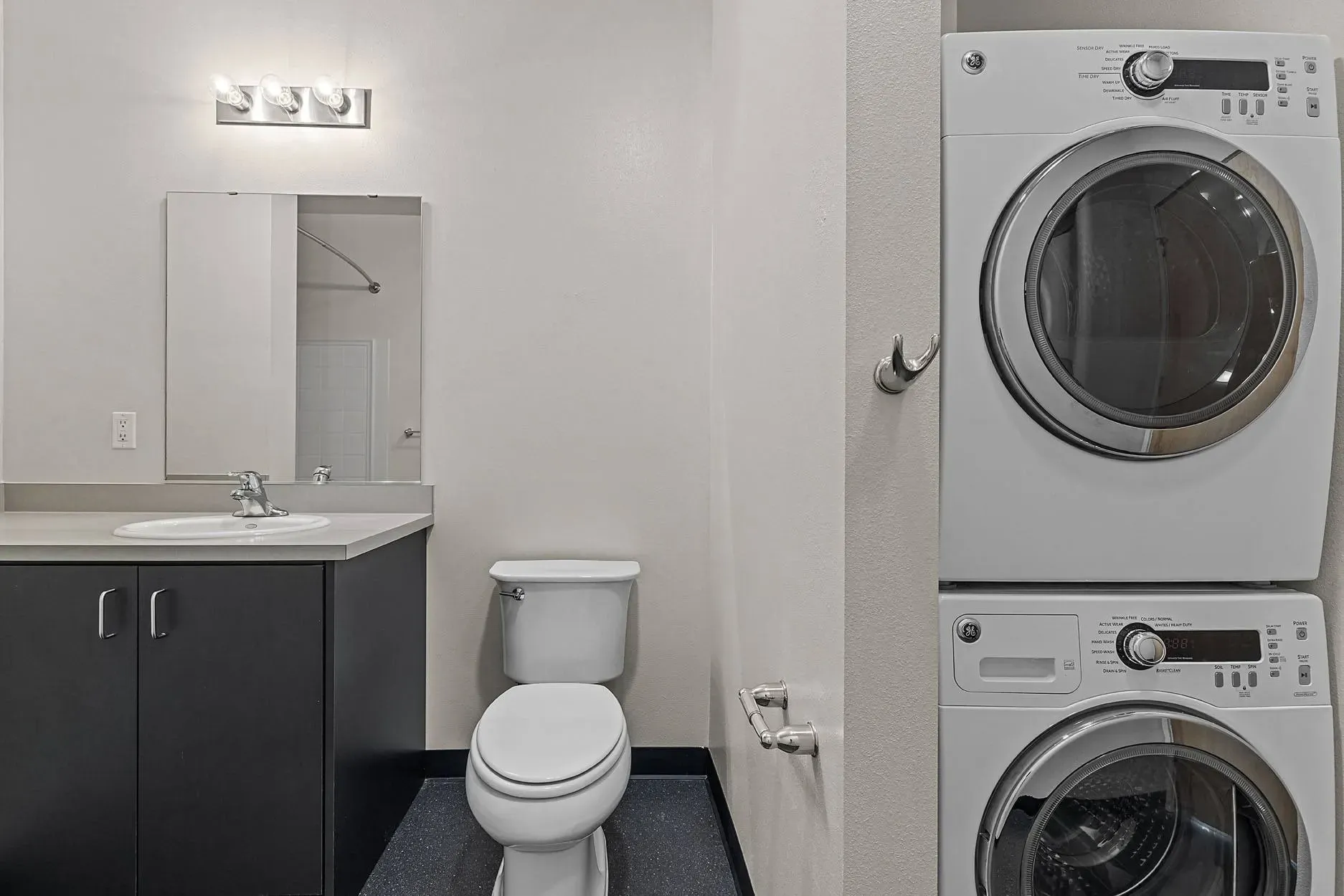 Bathroom with stacked washer and dryer, vanity, and toilet.
