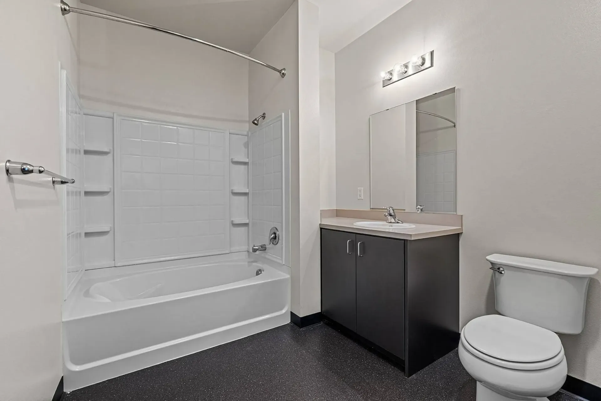 Modern bathroom with a white bathtub, shower, toilet, and vanity with a sink.