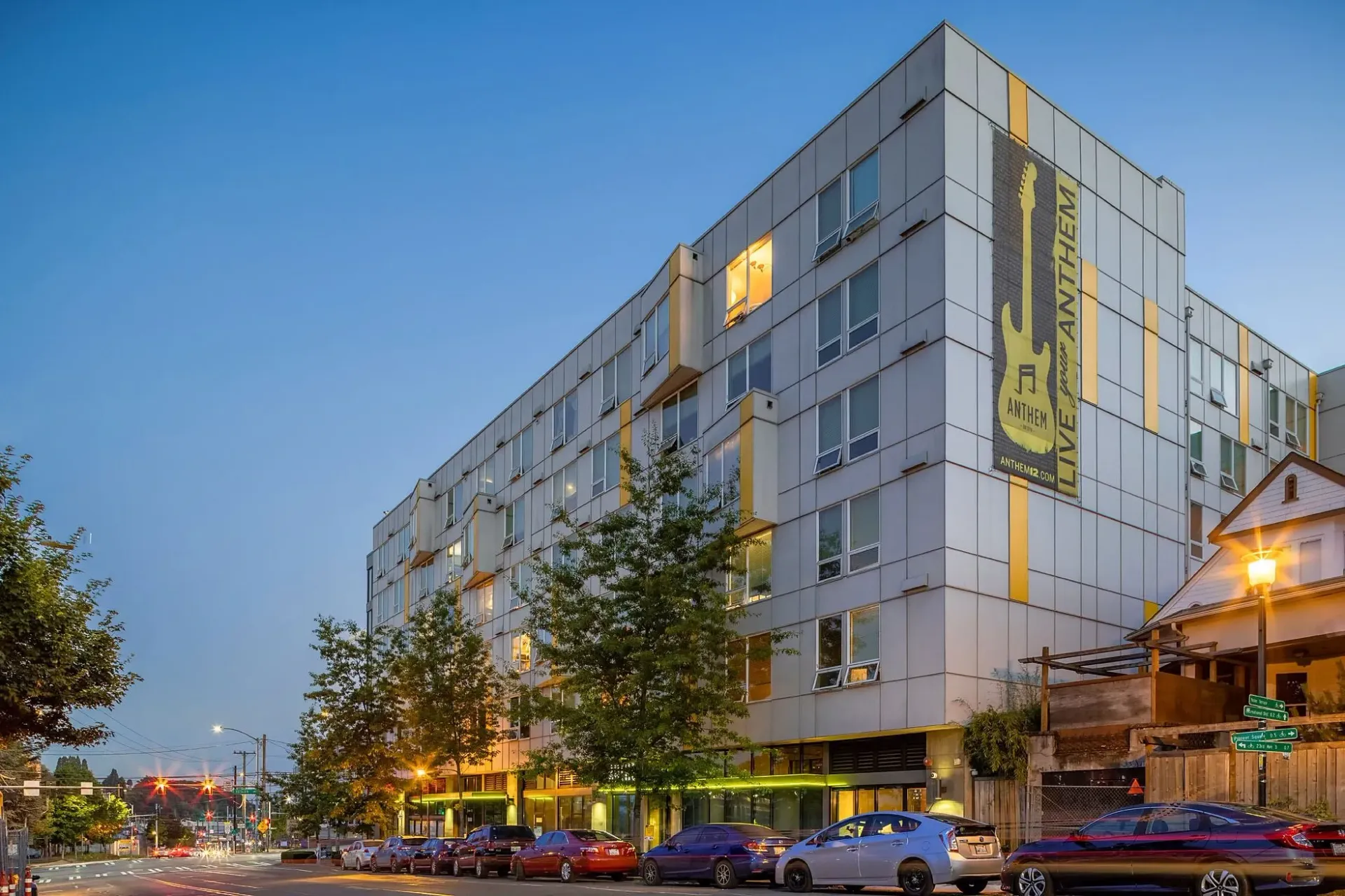 Exterior of the Anthem apartment building with a large guitar graphic and text 'LIVE your ANTHEM'.