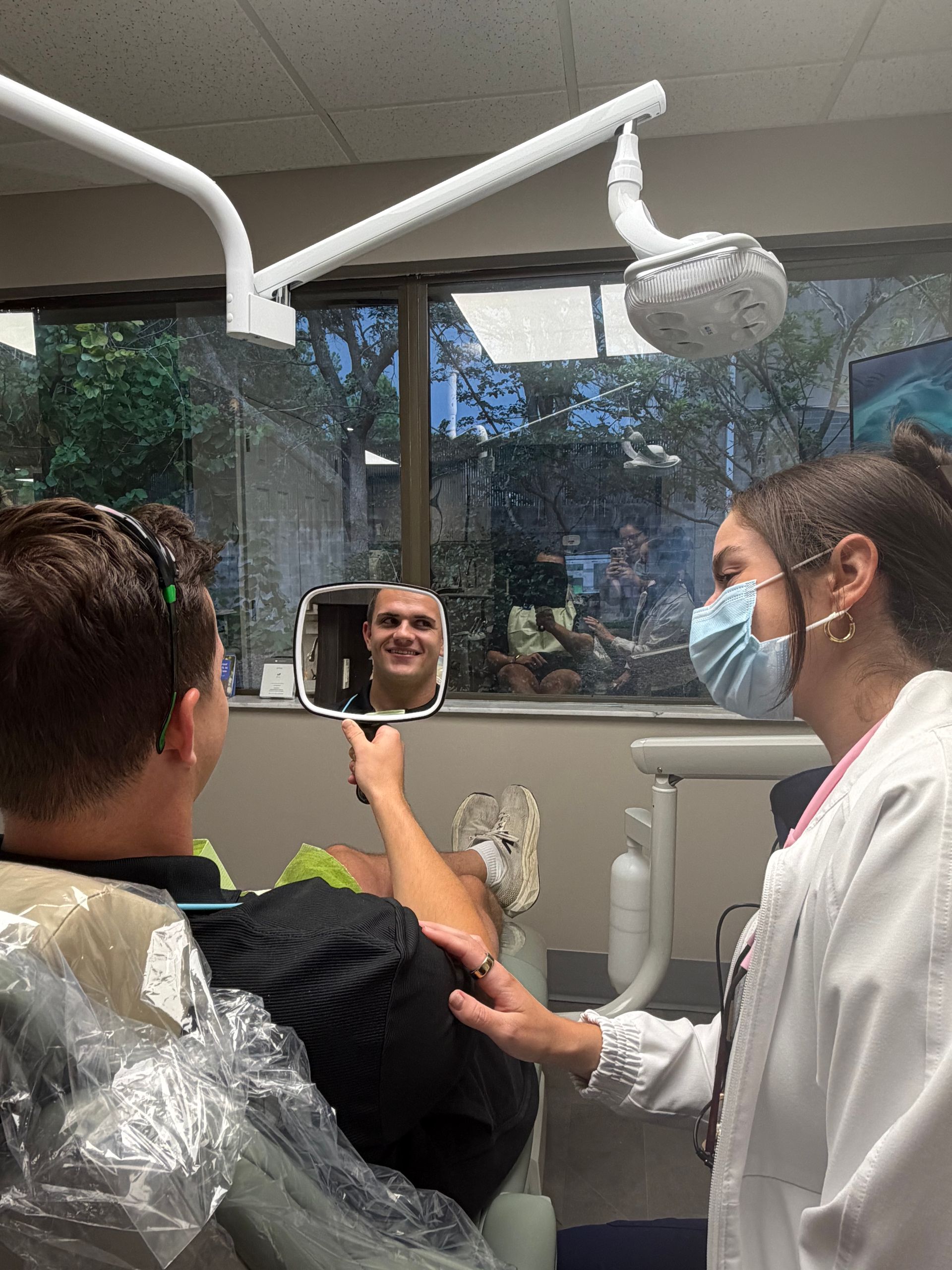 Dentist in blue gloves showing a small dental model to a smiling patient in a clinic