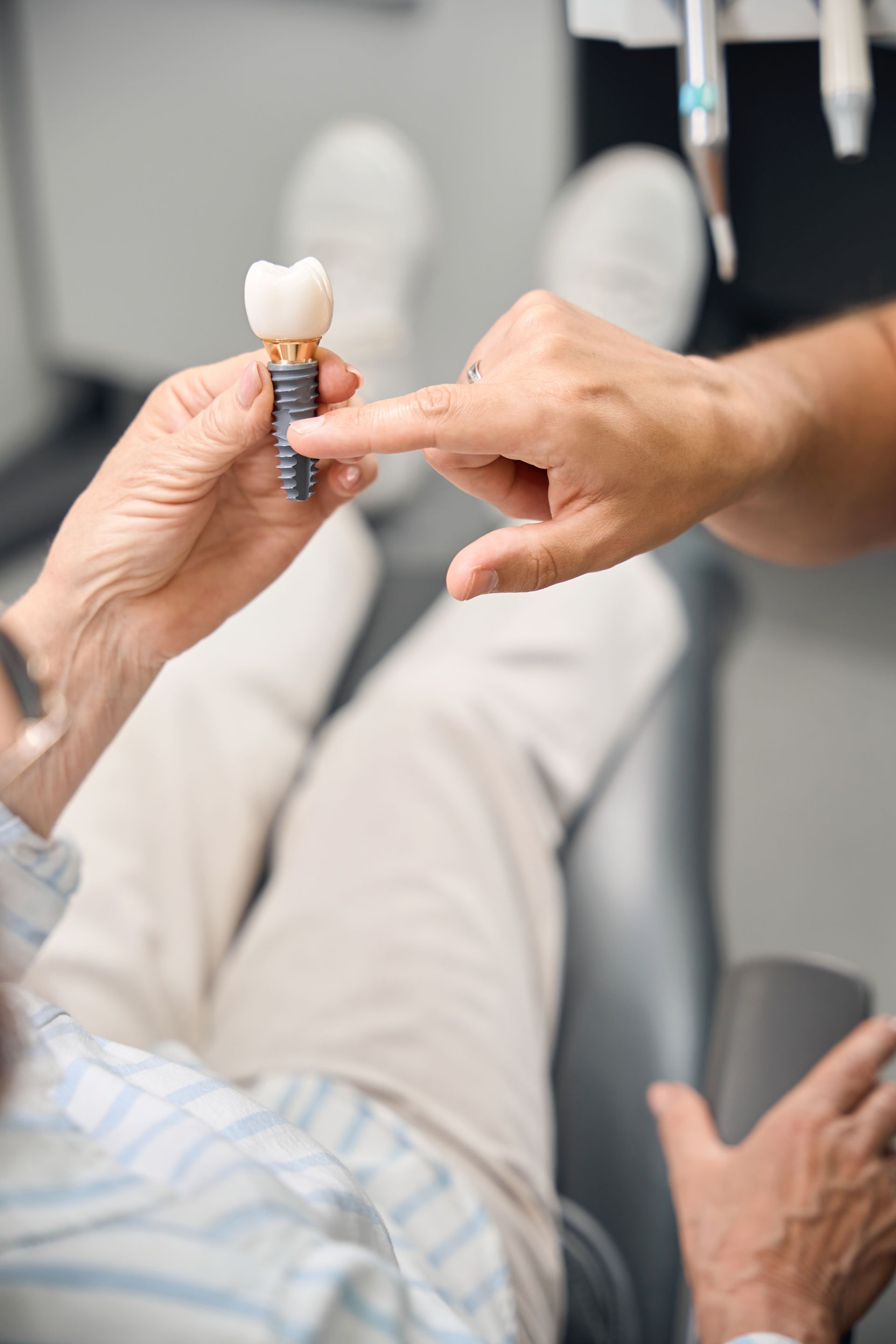 Dentist showing a tooth model to a patient reclining in a chair