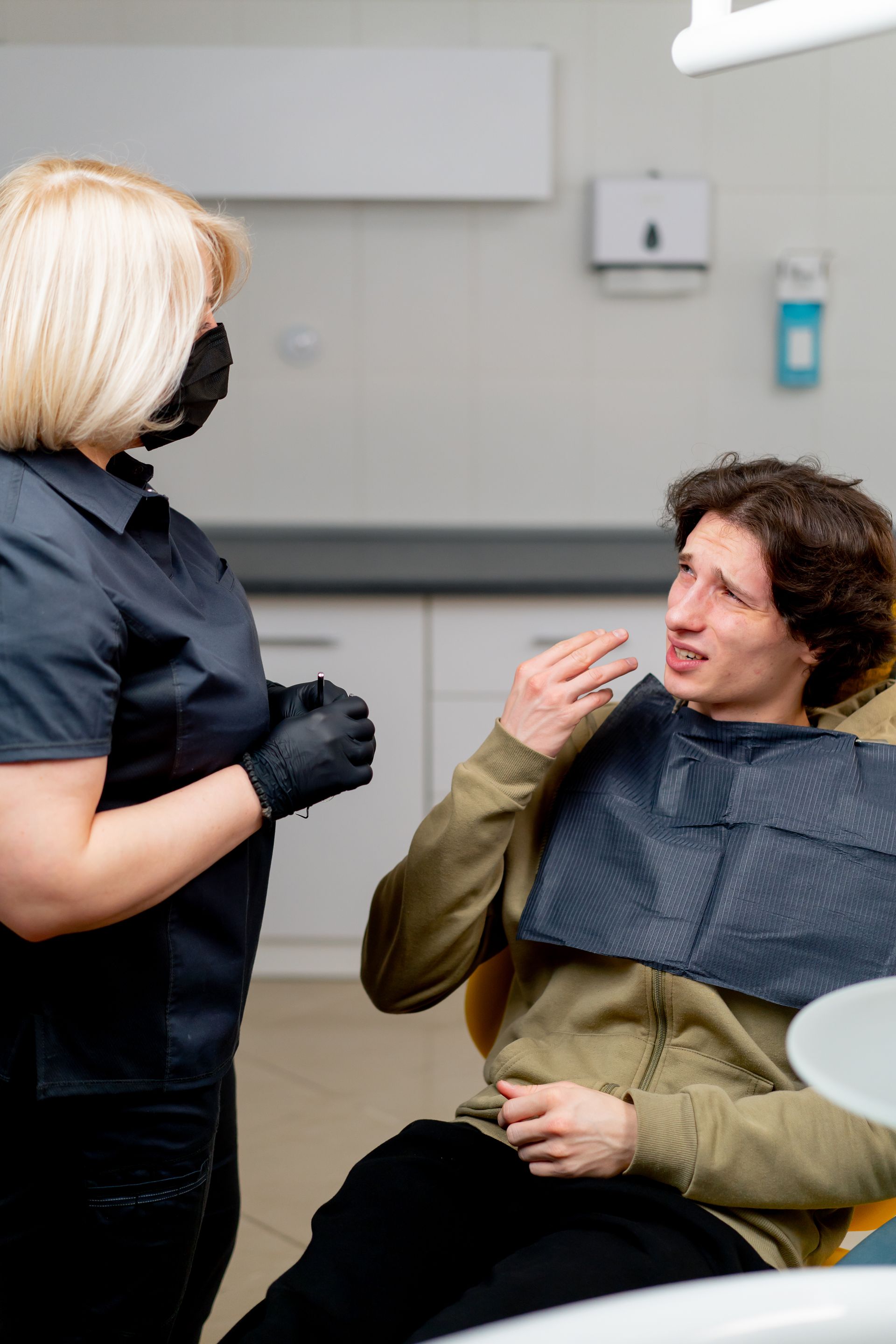 Dentist speaking with a seated patient in a dental chair during an exam