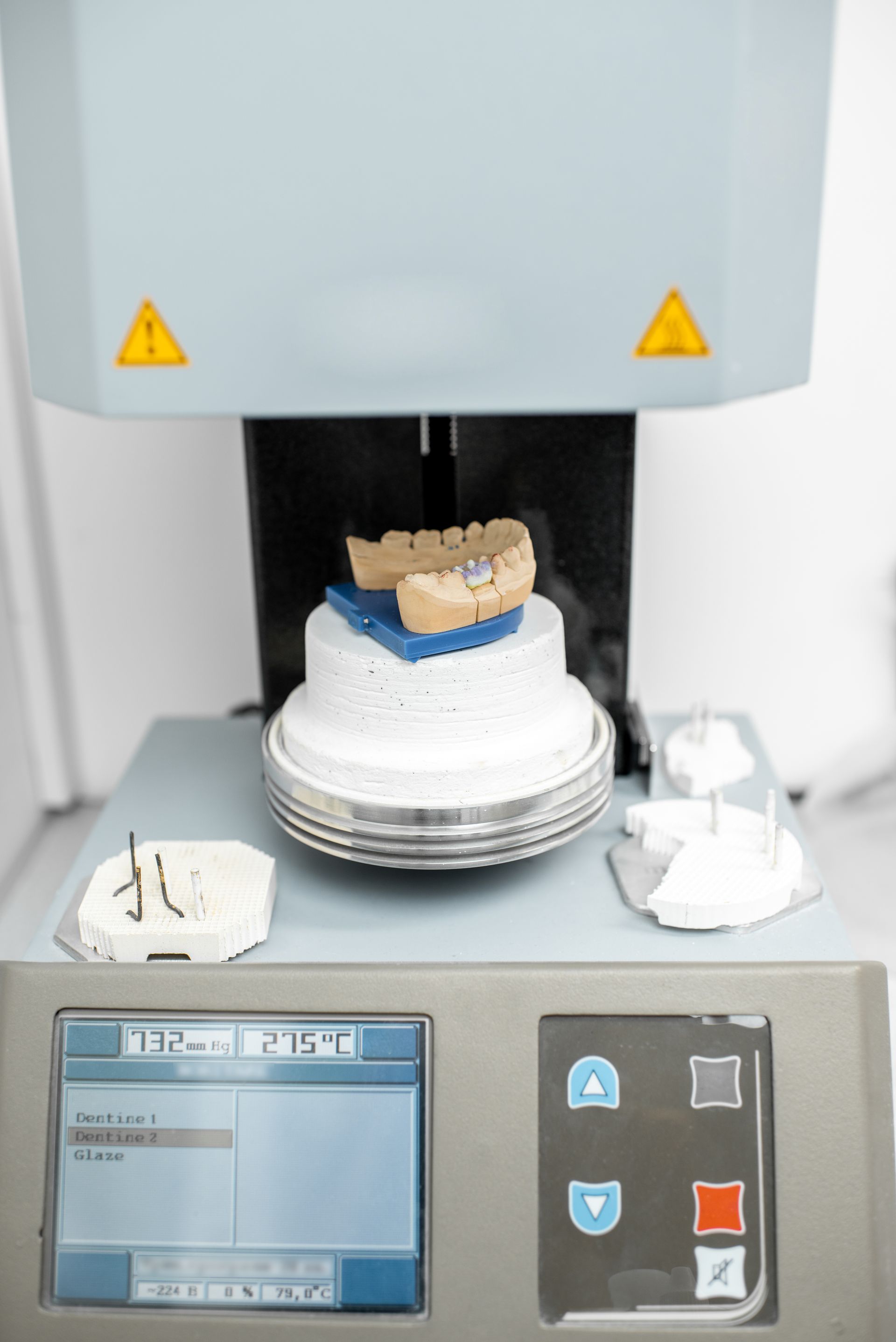 Dental milling machine carving a crown on a rotating platform with a control panel below