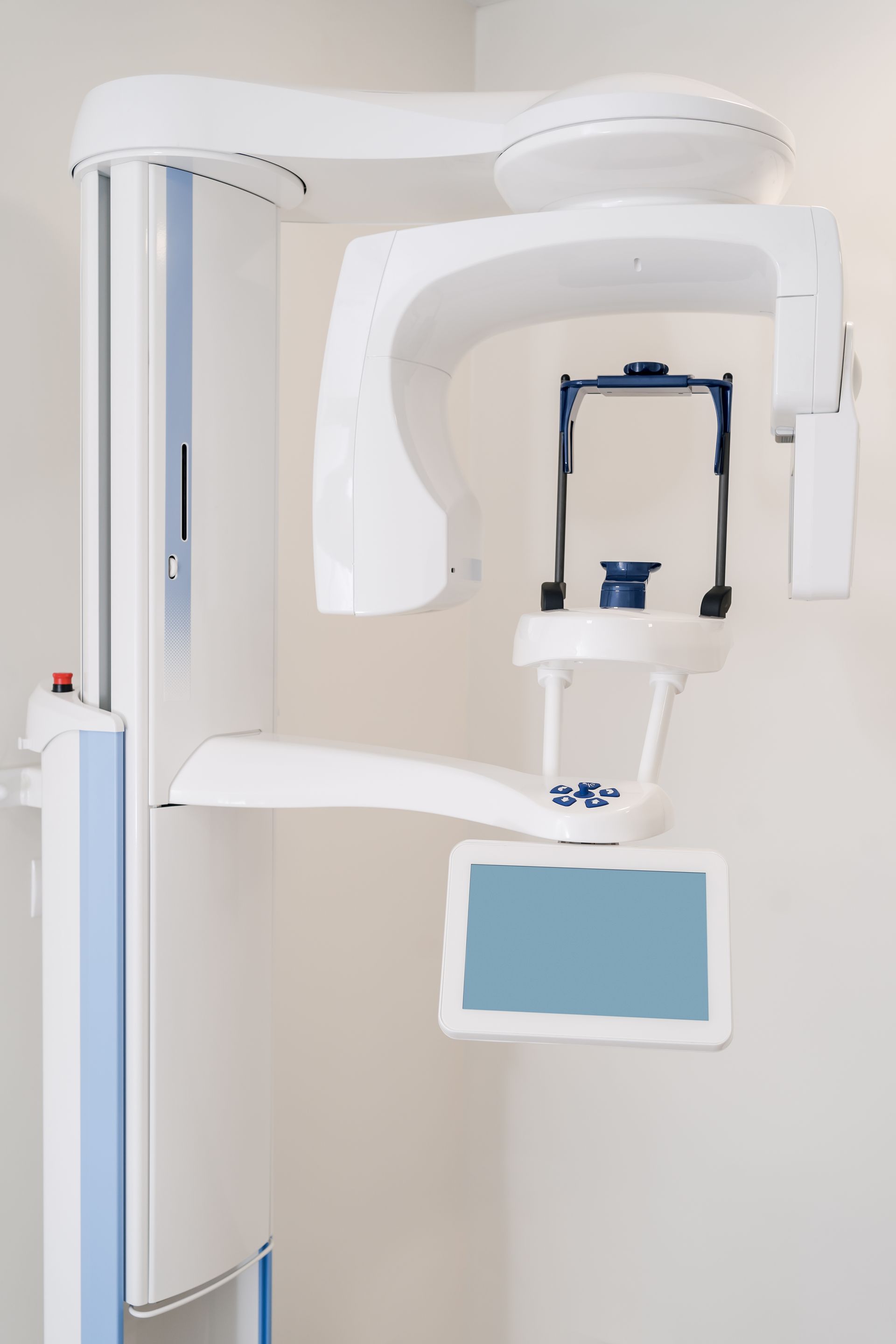 Dental X-ray machine with white arm and blue monitor in a clinic room