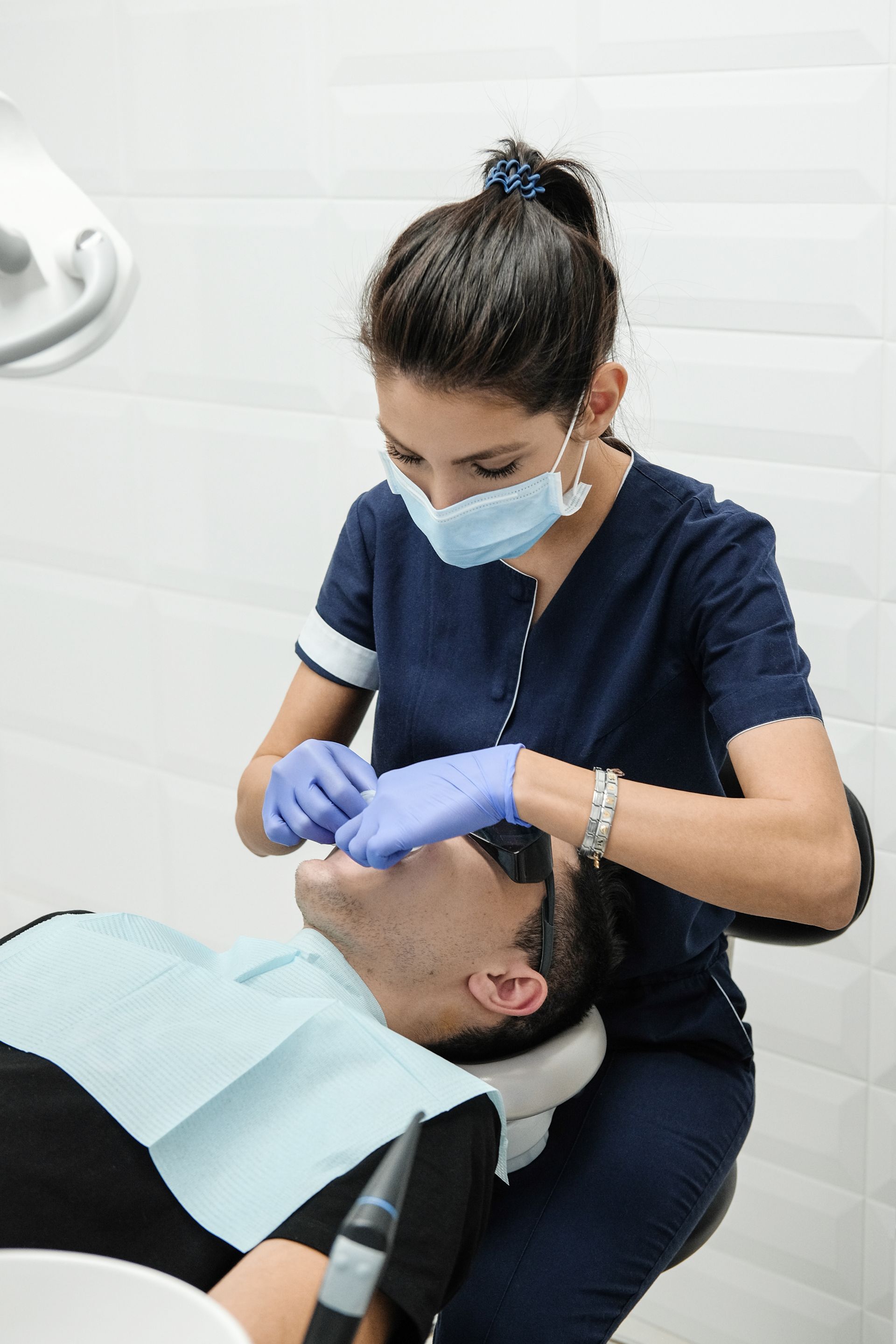 Dentist examining a patient’s teeth in a clinic, wearing gloves and a mask