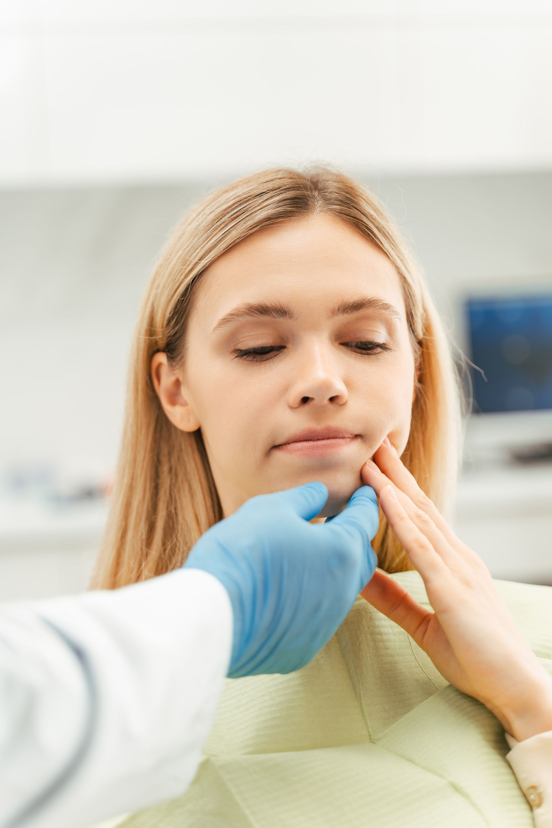 Healthcare worker examining a patient’s jaw and chin in a clinical setting