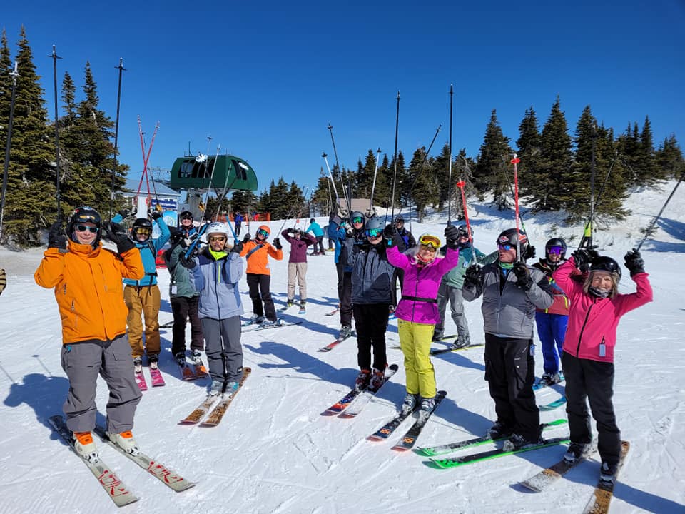 Skiers posing with raised arms on a snowy slope under a clear blue sky