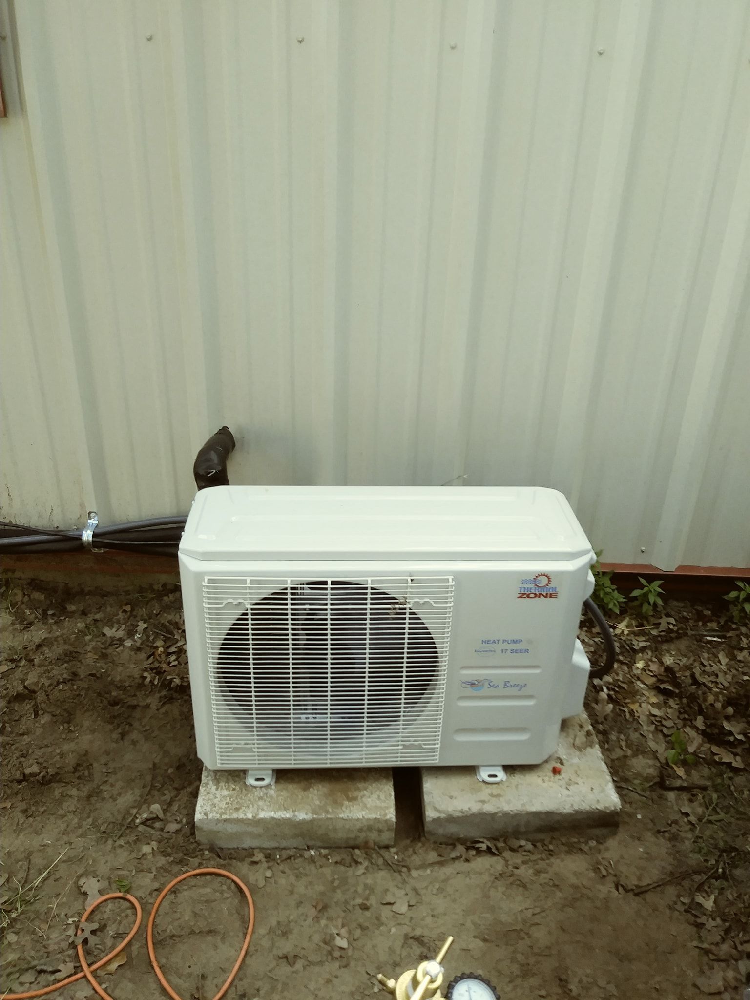 a white air conditioner is sitting on a concrete block in front of a building .