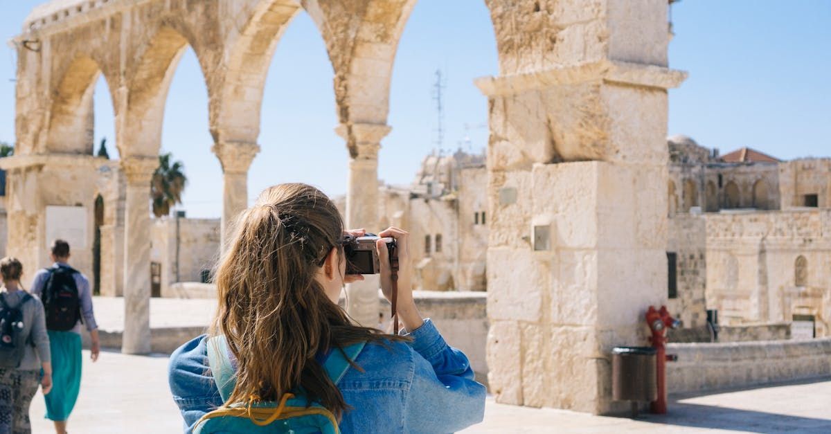 A young girl is taking a picture of a building with a camera.