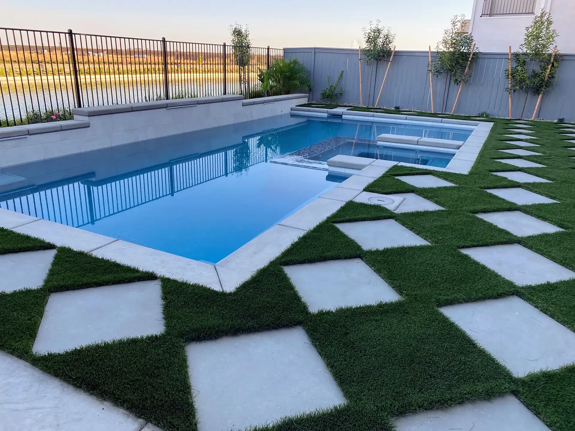 Swimming pool with square stepping stones in green grass.