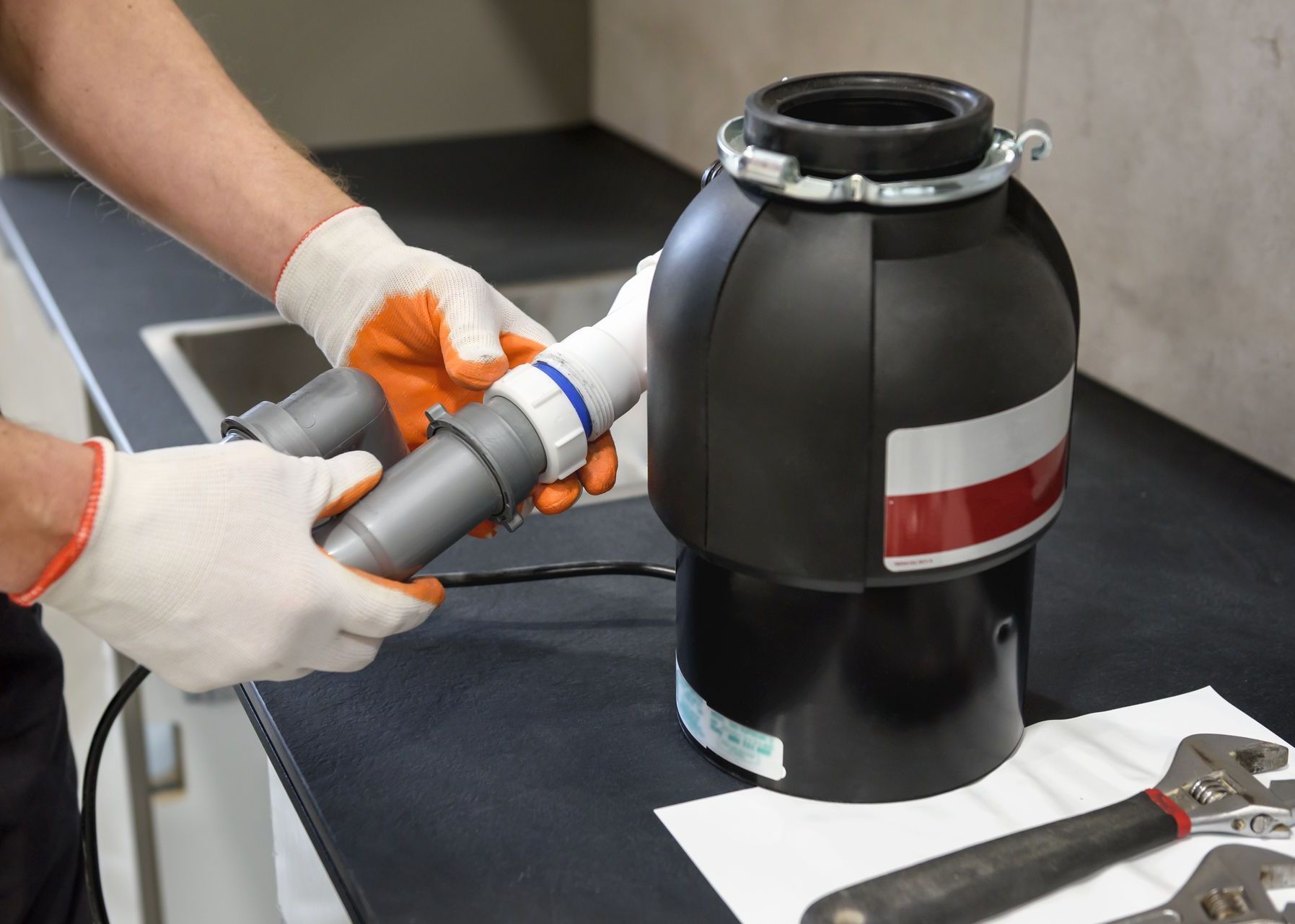 Technician repairing a kitchen garbage disposal system, providing trusted Plumbing services in Copley for local homeowners.