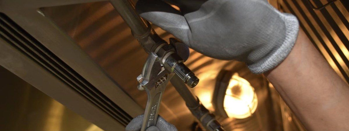 Plumbing services in Hudson: a technician tightening a pipe fitting, Unique Plumbing & Drain, Inc.