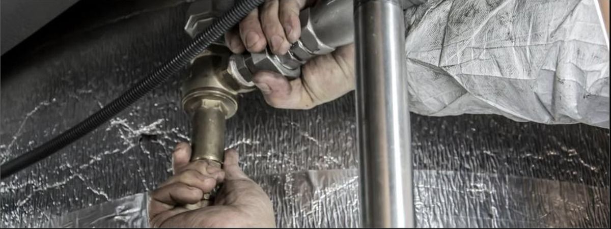 Plumber tightening brass trap under sink, plumbers in Bath and Canton, Unique Plumbing