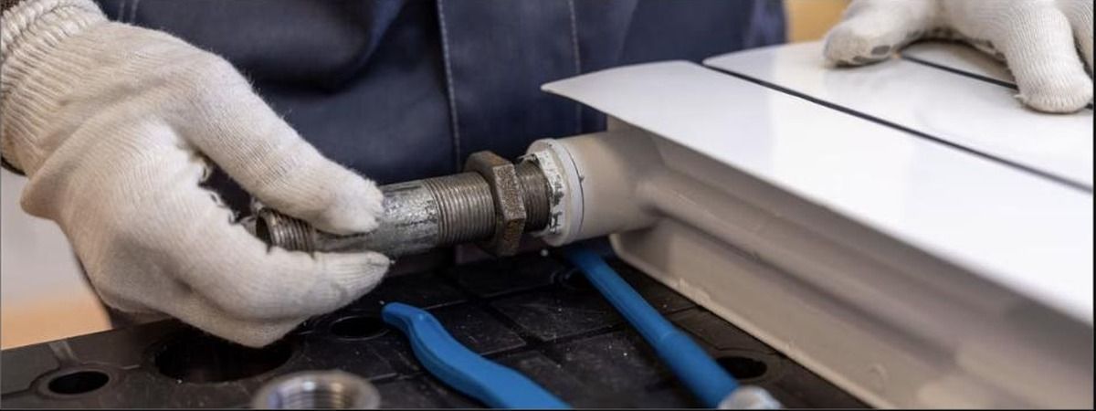 Gloved plumber threading steel pipe fitting, choosing plumbers in Akron, Unique Plumbing
