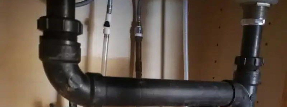 Black drain pipes under a kitchen sink for kitchen plumbing in Hartville