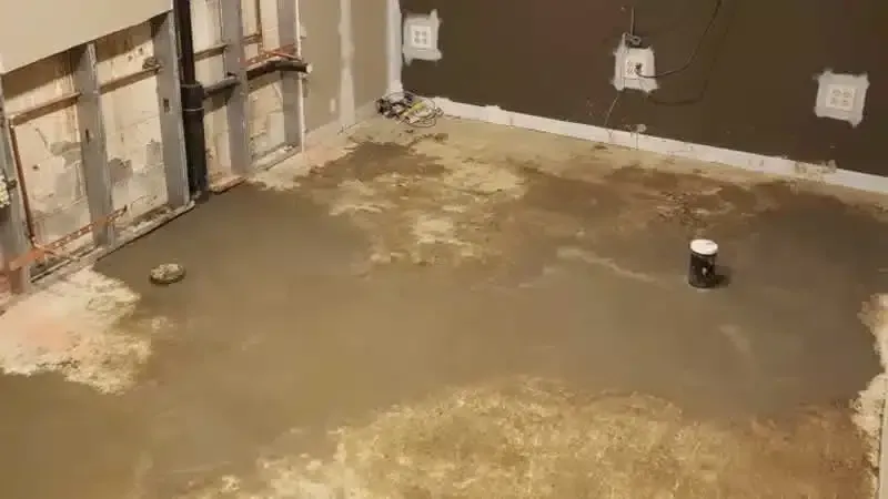 Freshly poured concrete floor with exposed pipes and walls during Plumbing Repair Youngstown renovation project.
