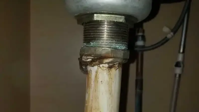 Sink drain pipes and connections, corroded and stained.