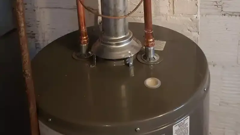 Grey water heater with copper pipes in a basement setting.