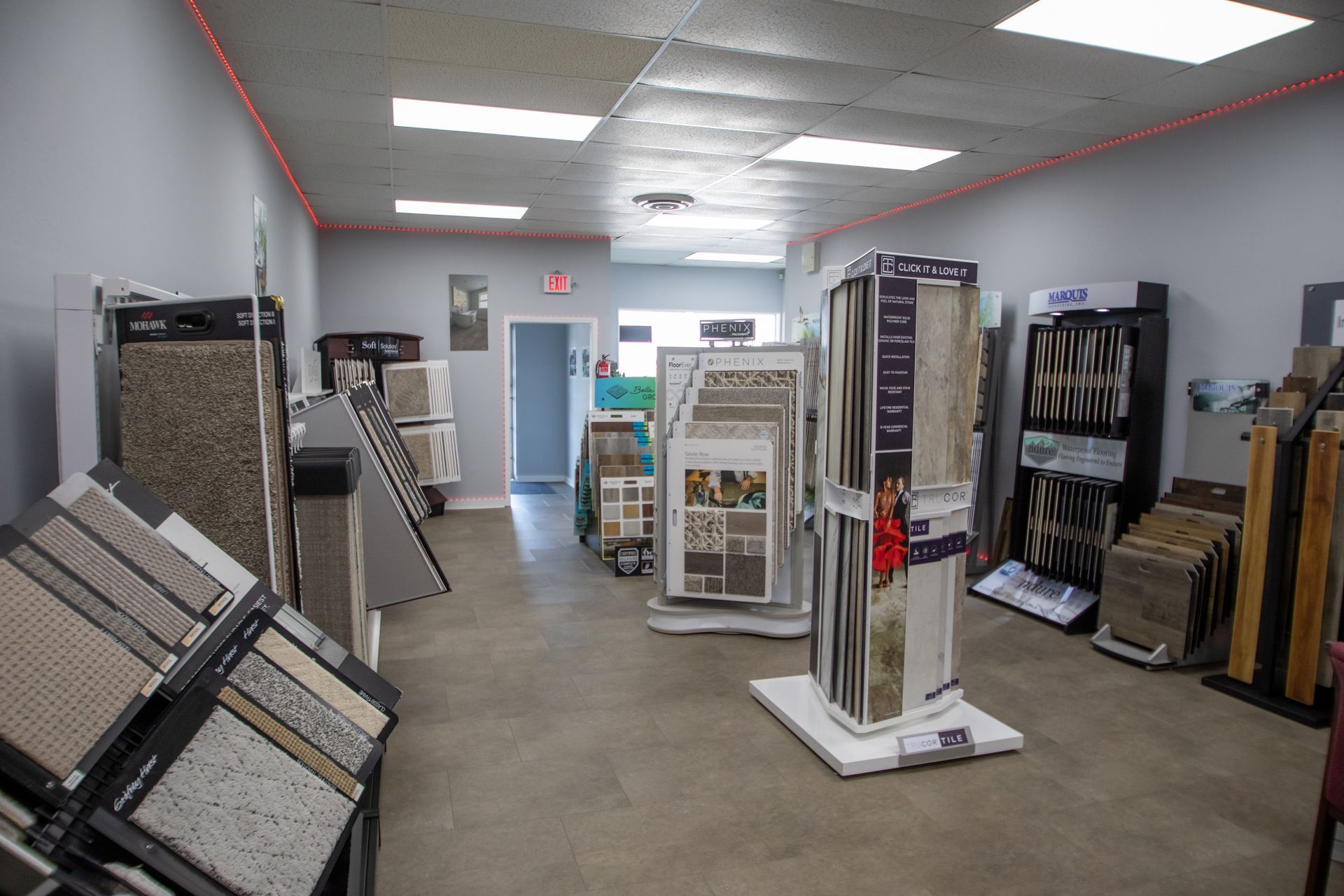 Interior of a tile store with displays of various flooring options and an open doorway.