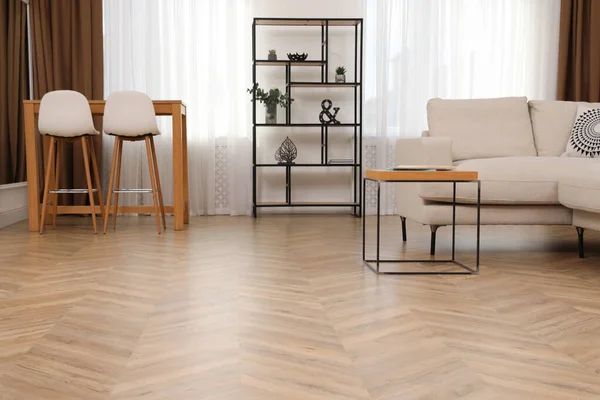 Living room with light wooden floors, white sofa, bar table with stools, and black shelving unit.