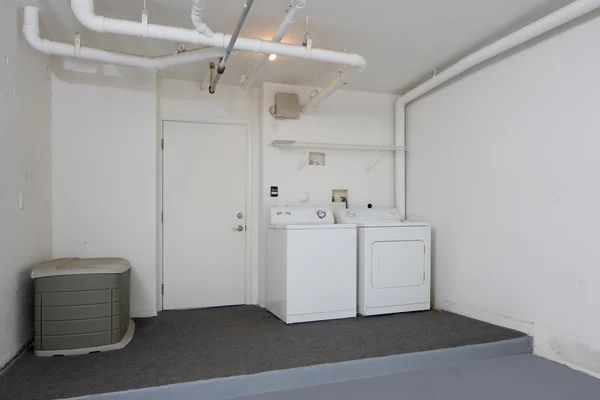 Laundry room with white washer and dryer, white door, and gray flooring.