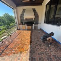 A man is kneeling on a brick floor in a room.