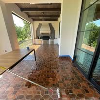 A broom is sitting on a brick floor in a room.