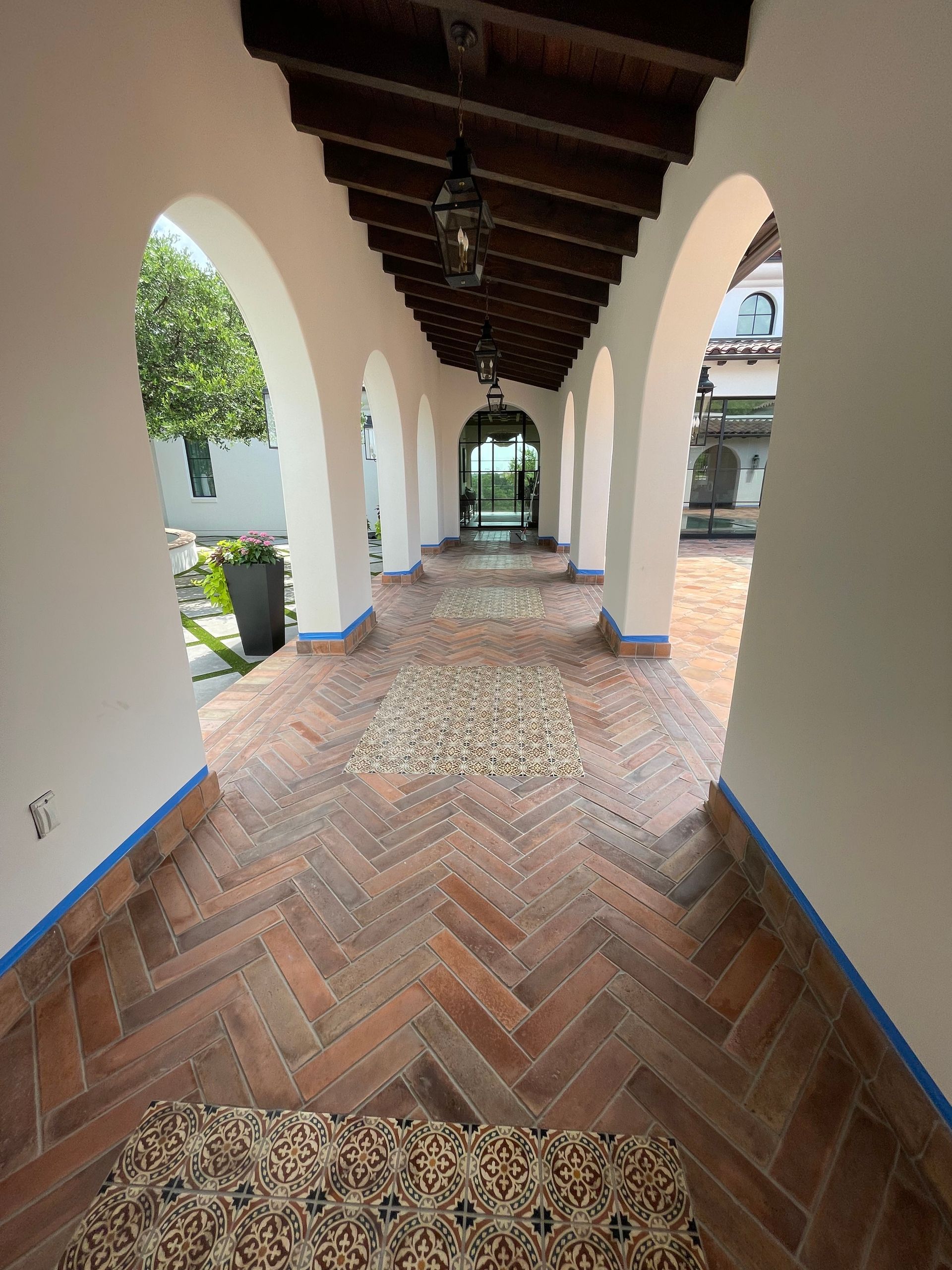 A long hallway with arches and a herringbone floor