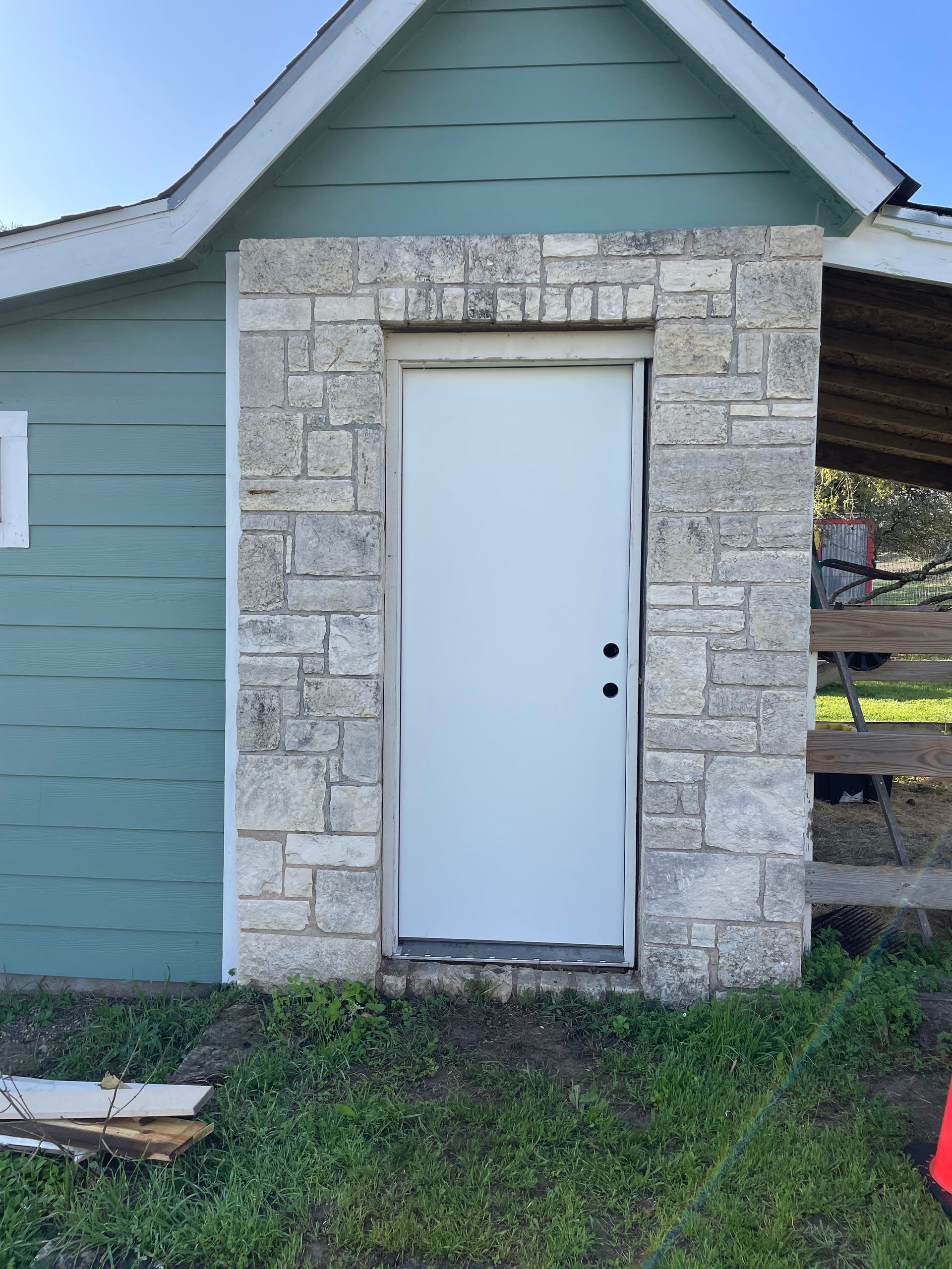 A white door is surrounded by stone on the side of a building