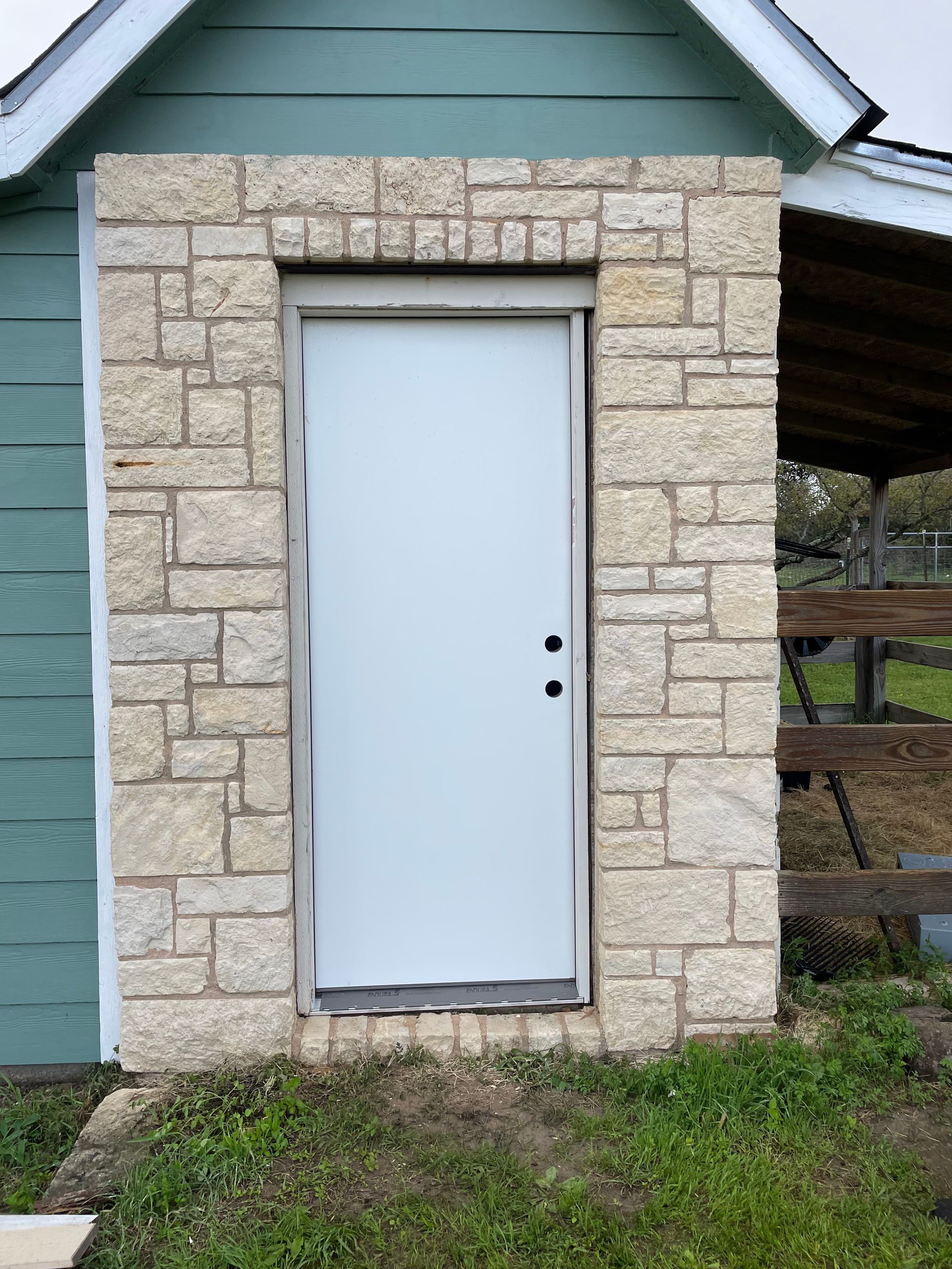 A white door is surrounded by a stone wall