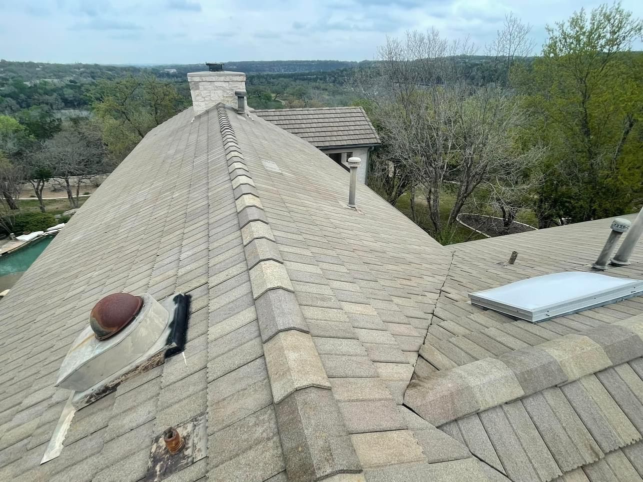 A roof with a skylight and a chimney on it.