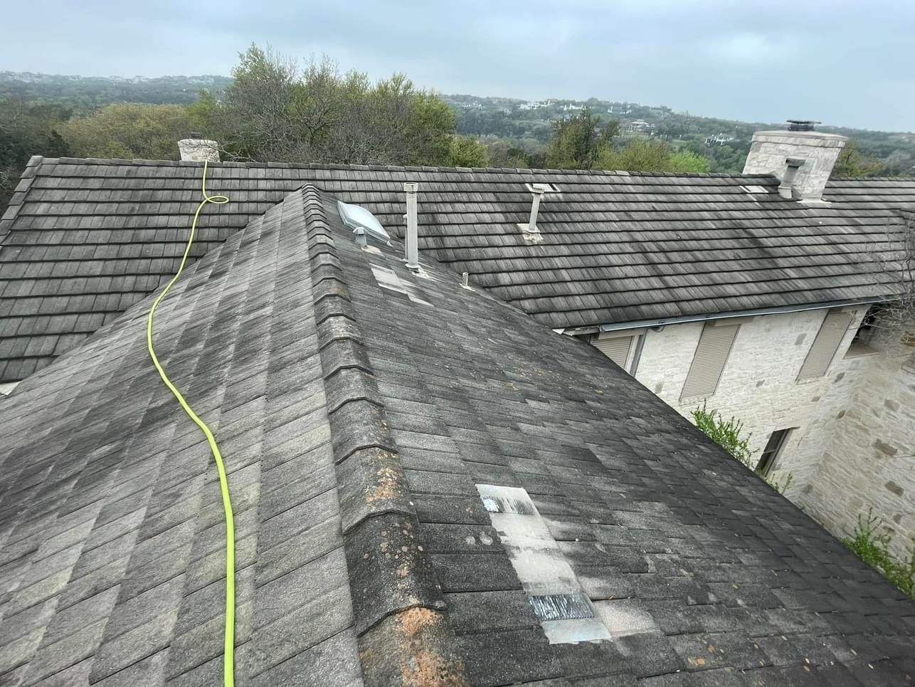 The roof of a house with a yellow hose attached to it.