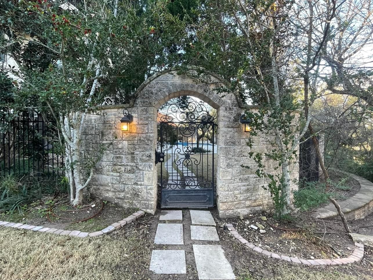 There is a stone wall with a gate in the middle of it.