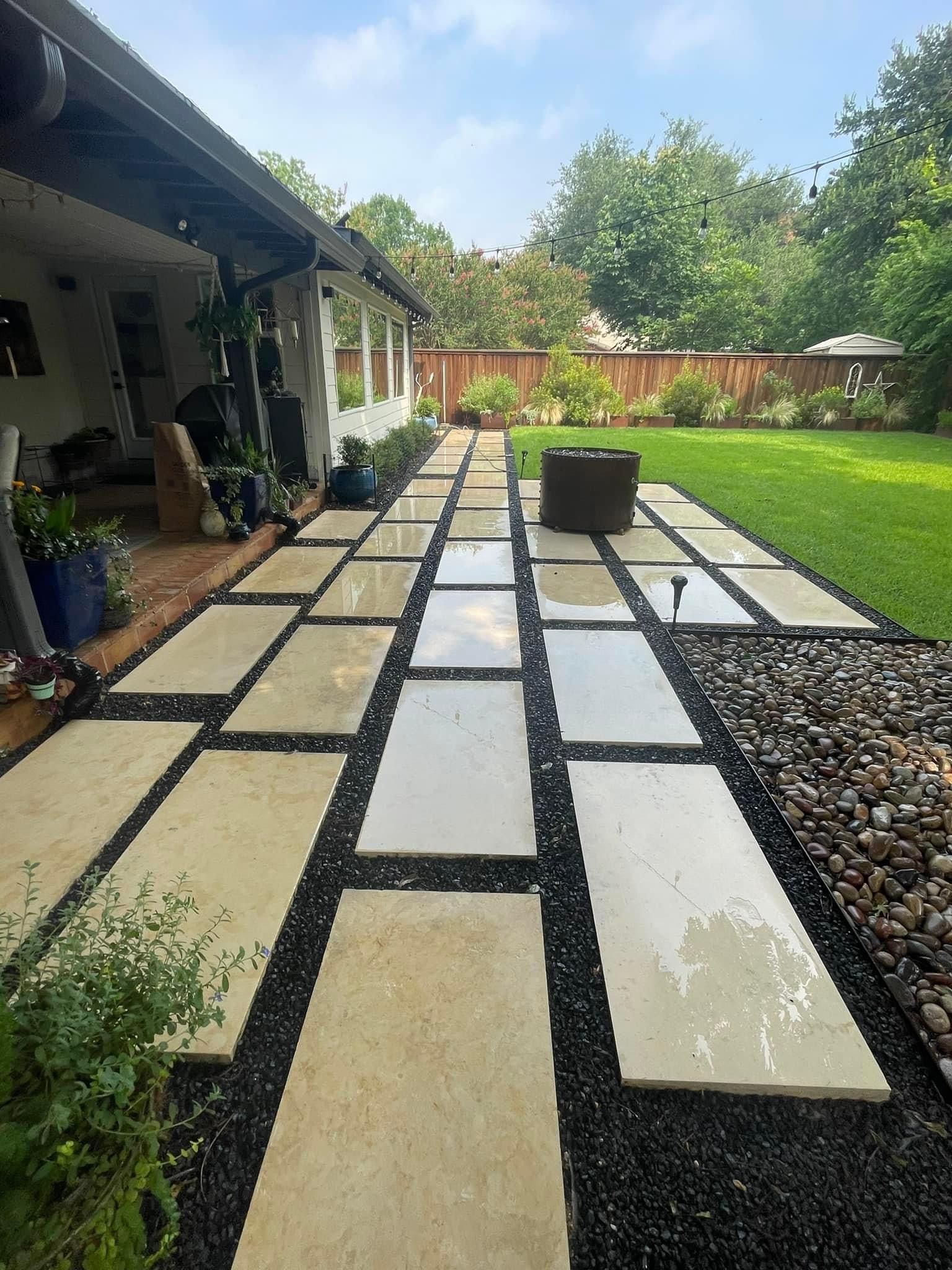 A walkway leading to a house with a fire pit in the backyard.