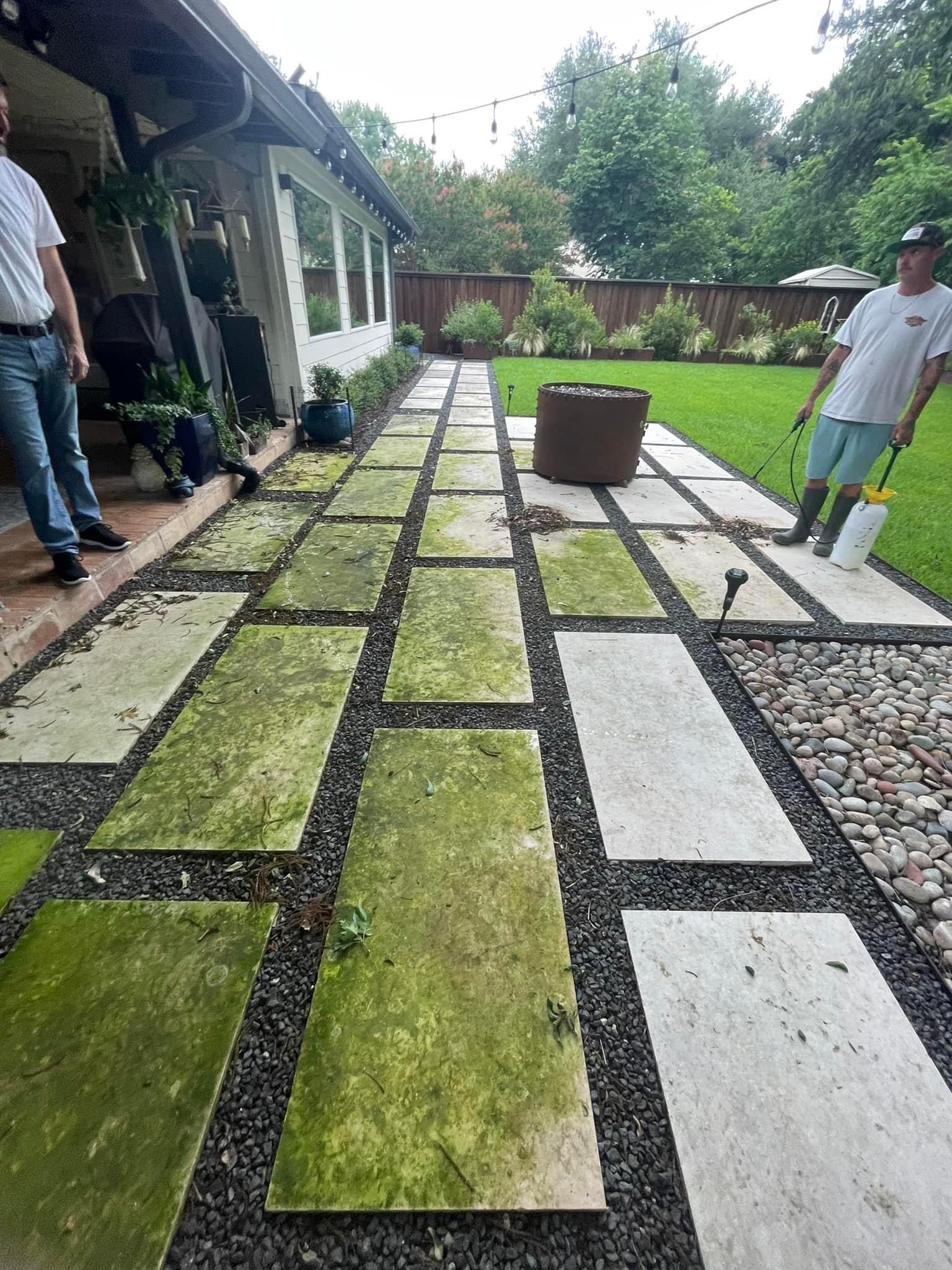 Two men are standing on a stone walkway with moss on it.