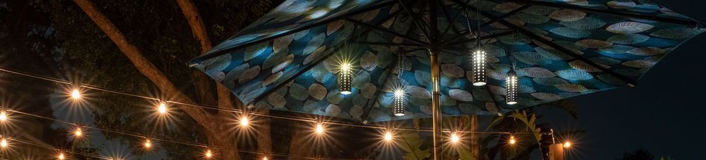 A nighttime outdoor scene featuring string lights and a patio umbrella with a blue and white patterned fabric.