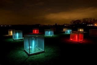 Glowing cubes in blue and red are arranged across a dark grassy field at night, casting soft light on the surrounding ground.