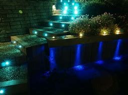 Night view of stone stairs illuminated with blue accent lights, glowing step markers, and soft landscape lighting.