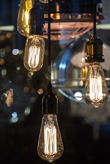 Several vintage-style Edison bulbs hang in a cluster, glowing warmly against a dark, out-of-focus background.