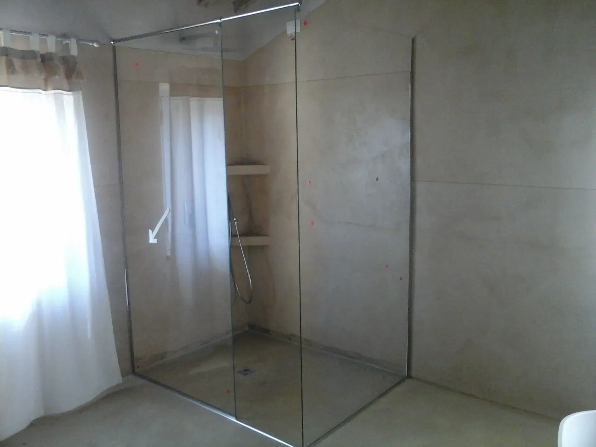 Doccia ad angolo con pareti in vetro trasparente e tenda velata in un bagno piastrellato.