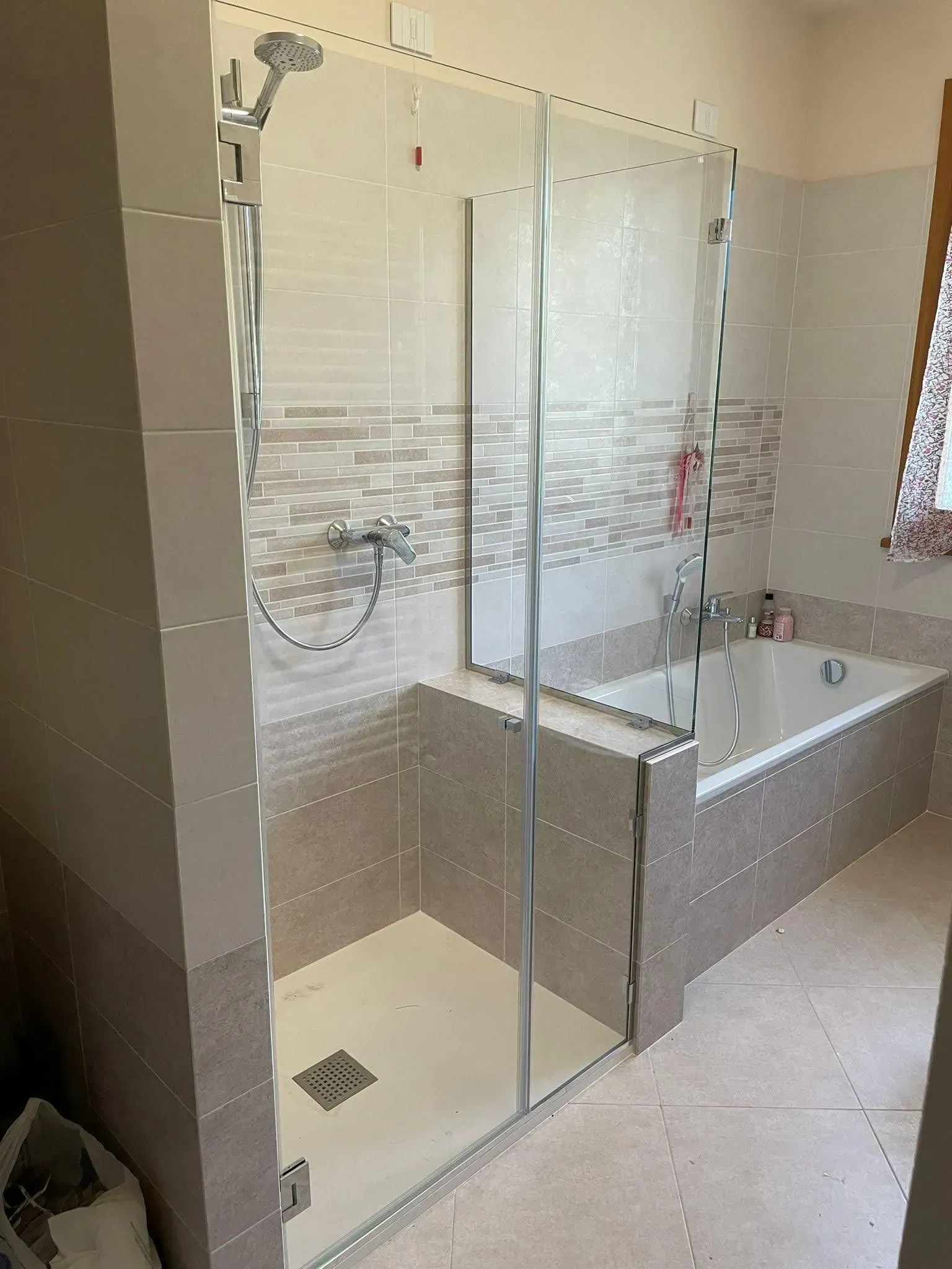 Bagno moderno con box doccia in vetro, doccia a parete e vasca freestanding.