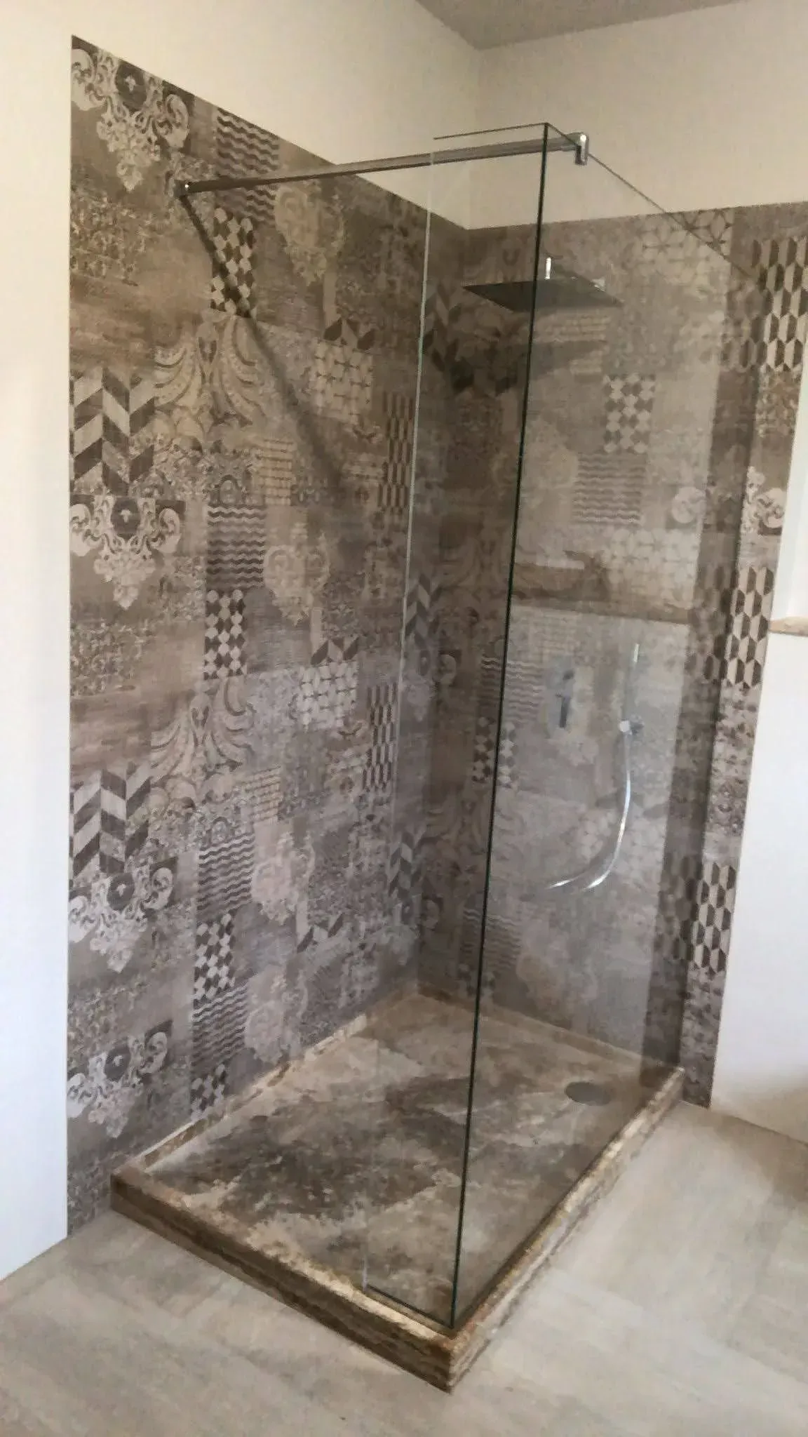 Cabina doccia moderna con pareti rivestite in piastrelle effetto pietra e box doccia in vetro.