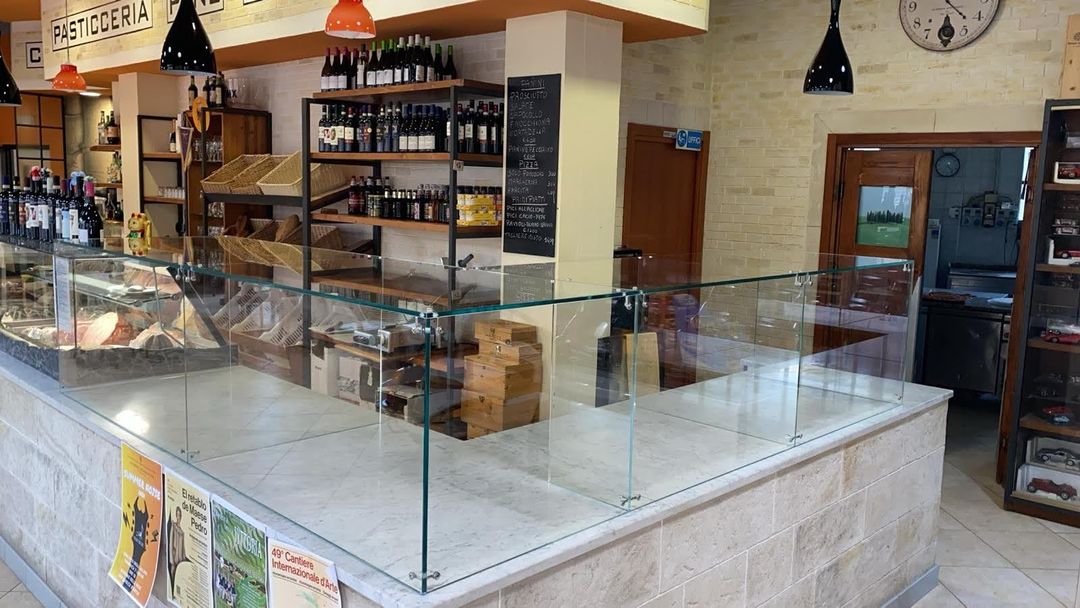 Bancone di una caffetteria-panetteria con vetrine, pasticcini, scaffali e luci a sospensione.