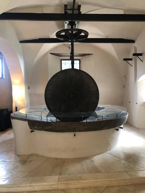 Grande pietra circolare nera in una sala museale bianca con soffitto a volta e travi in legno