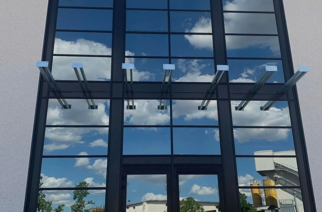 Edificio moderno con facciata in vetro che riflette il cielo azzurro e le nuvole.