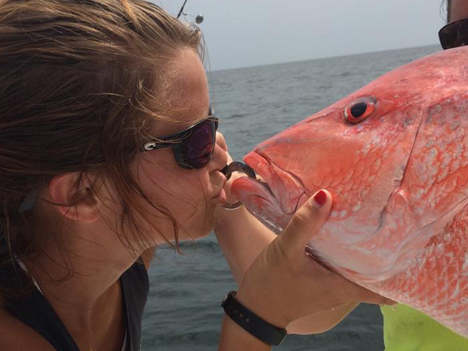 A man and a woman holding a large red fish