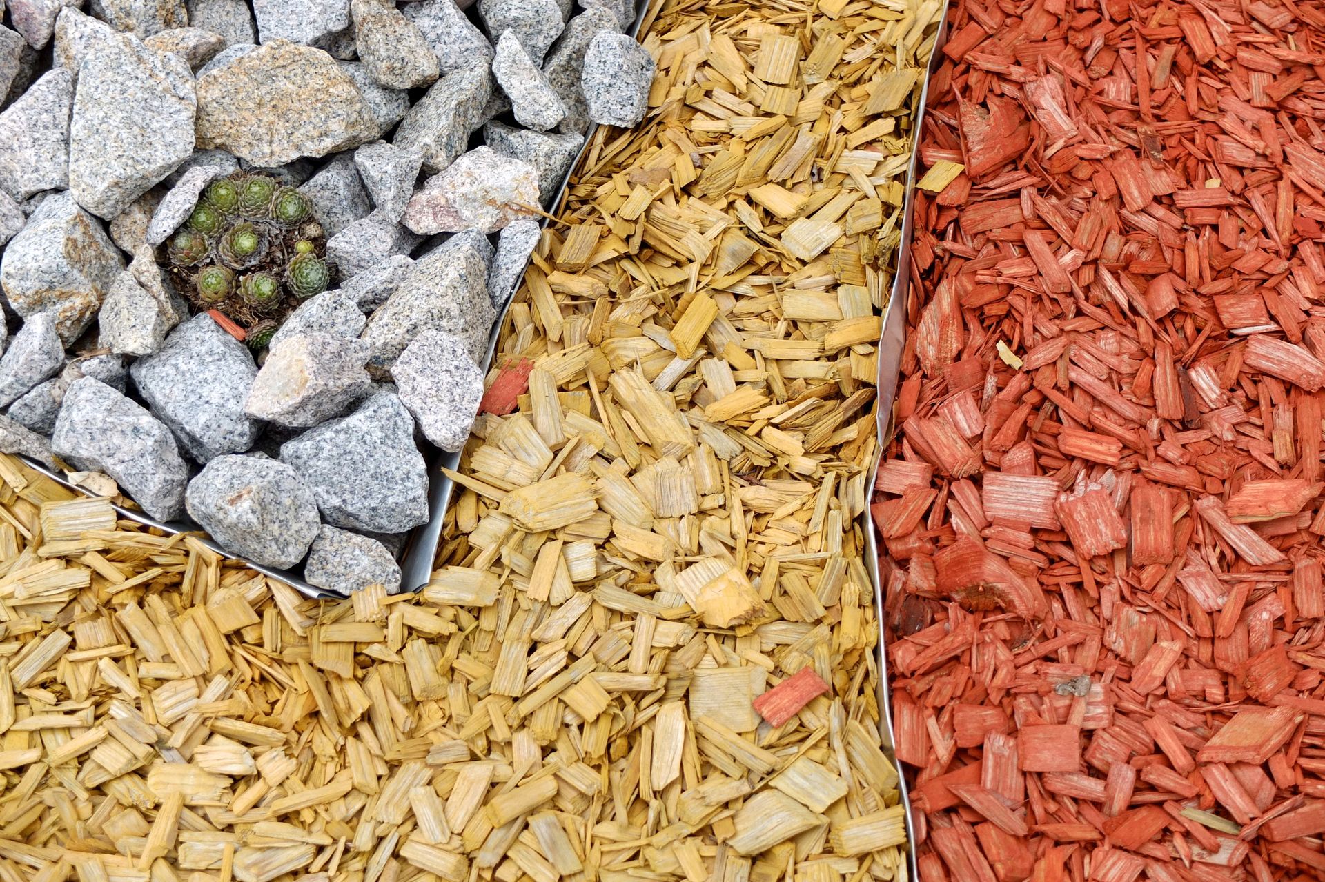 Three distinct garden landscaping materials arranged in vertical strips: gray rocks, natural wood chips, and red mulch.