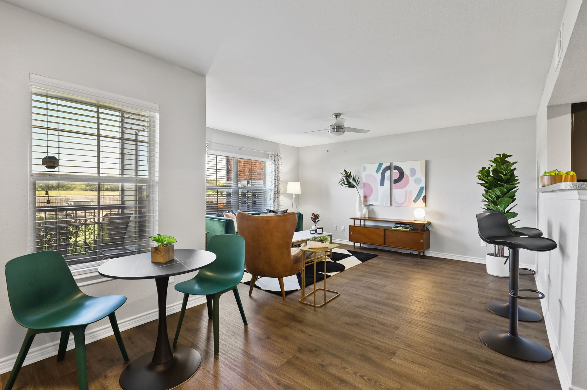 Living room with dining set, mid-century modern furniture, hardwood floors, and large window.