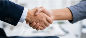 Two hands in a business handshake, one in a navy suit and one in a white sleeve